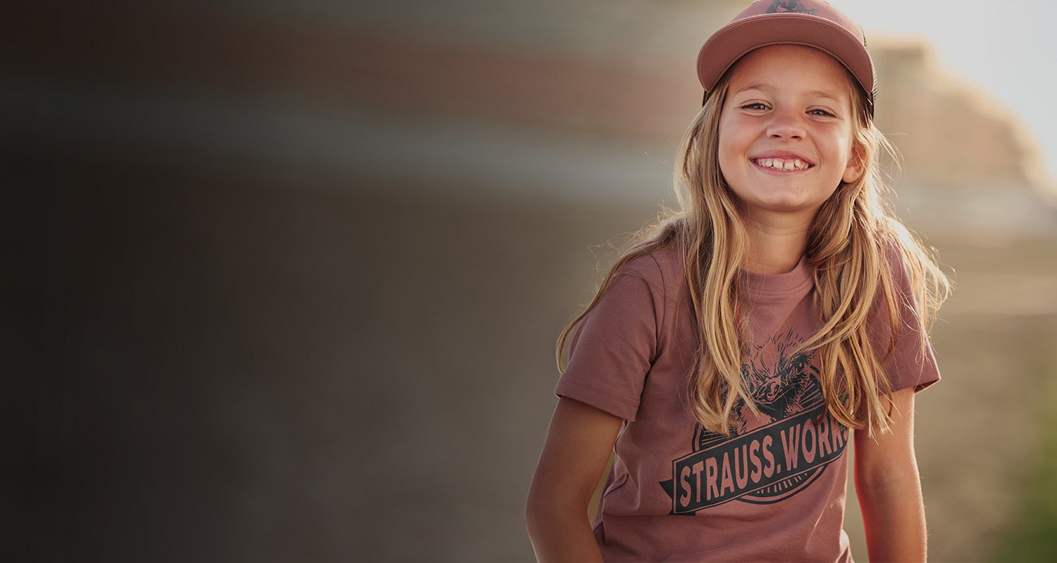 Kind trägt ein T-Shirt mit Strauss Print in oxidrot