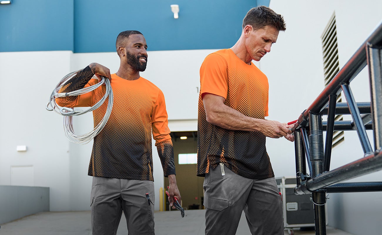 Zwei Männer tragen die neuen Funktionsshirts der e.s.T:aktik im Einsatz beim Aufbau von Veranstaltungstechnik