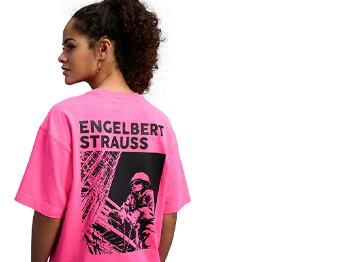 Eine Frau von hinten, der ein neonpinkes Vintage-Shirt trägt. Auf dem Rücken ist ein cooler Print mit dem Schriftzug engelbert strauss zu sehen.
