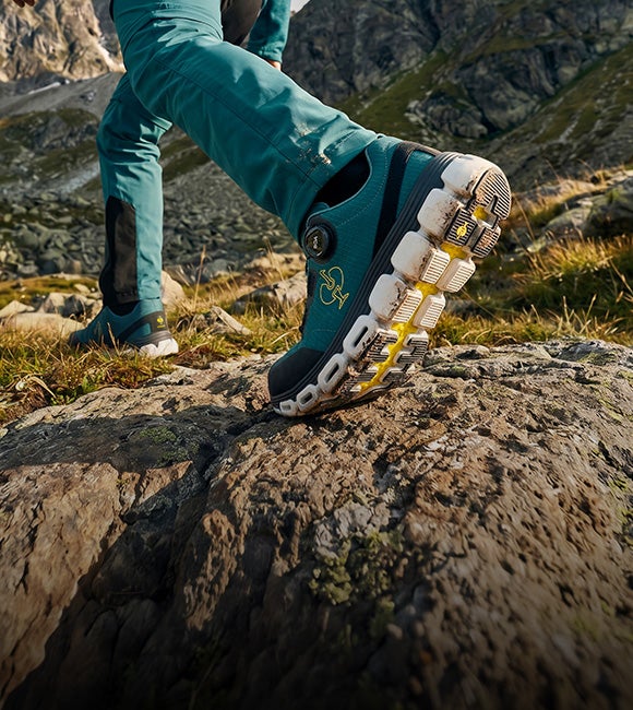 KI-generiert / modifiziert - Smaragdgrüne O1 Berufsschuhe e.s. Rexburg low auf einem Felsen im Freien mit eingeblendetem Schriftzug zu Arbeitsschuhen im Trail-Style.
