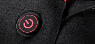 Gros plan sur l’interrupteur marche/arrêt lumineux avec symbole d’alimentation sur la veste chauffante e.s. Heizweste climafoam HW25.