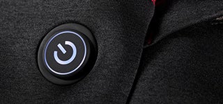 Gros plan sur l’interrupteur marche/arrêt lumineux avec symbole d’alimentation sur la veste chauffante e.s. Heizweste climafoam HW25.