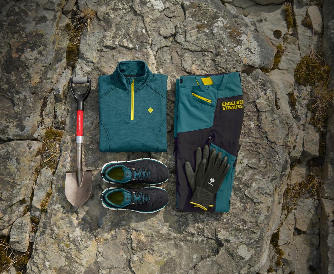 e.s.trail Troyer, Hose, Schuhe und Handschuhe neben einem Spaten auf Felsen