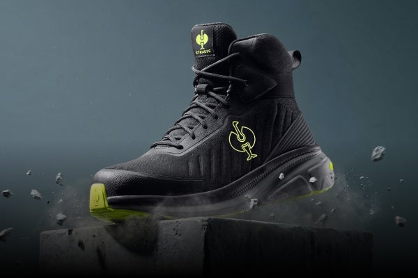 Schwarzer hoher Schuh mit gelben Details auf einem Betonblock.