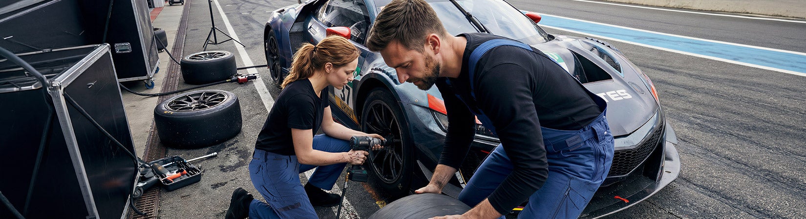 KI-gegenereerd / bewerkt - Twee personen verwisselen met gereedschap een band aan een raceauto in de pitstraat.