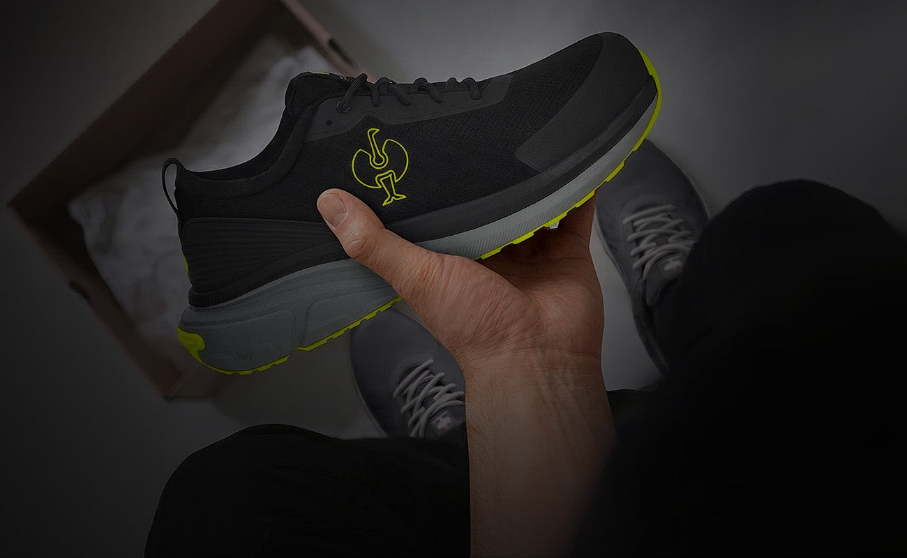 Une nouvelle chaussure de travail Strauss est tenue à la main au-dessus d’un carton vide