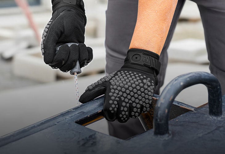 Hände in schwarzen Arbeitshandschuhen an einem Metallteil.