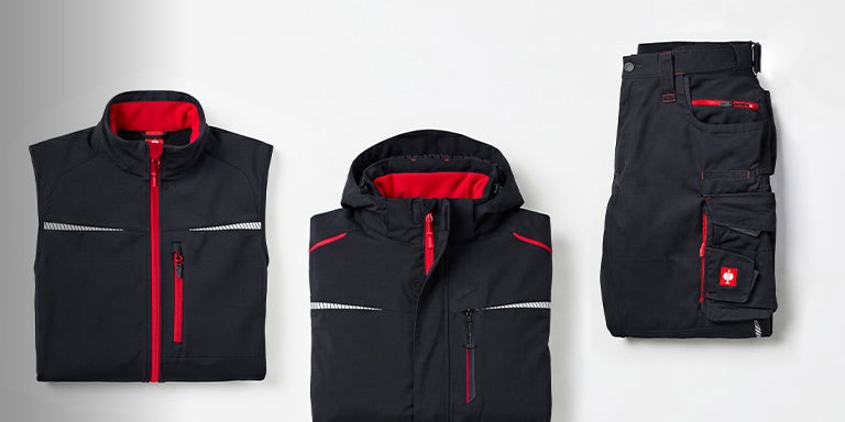 Gefaltete motion2020 Weste, Jacke und Hose in graphit/feuerrot auf grauem Hintergrund