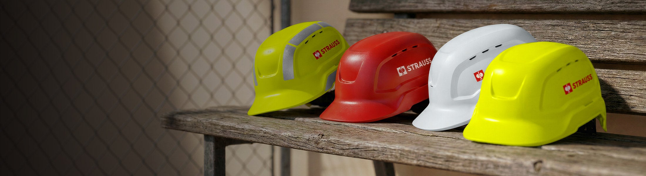Généré / modifié par IA - Quatre casques de sécurité jaunes, rouge, blanc et jaune sont posés sur un banc en bois.
