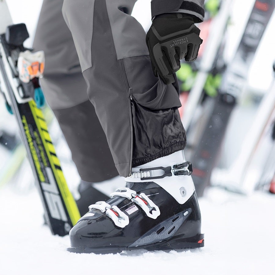 L’homme porte un pantalon de fonction e.s.trail snow en gris carbone / gris basalte avec des chaussures de ski
