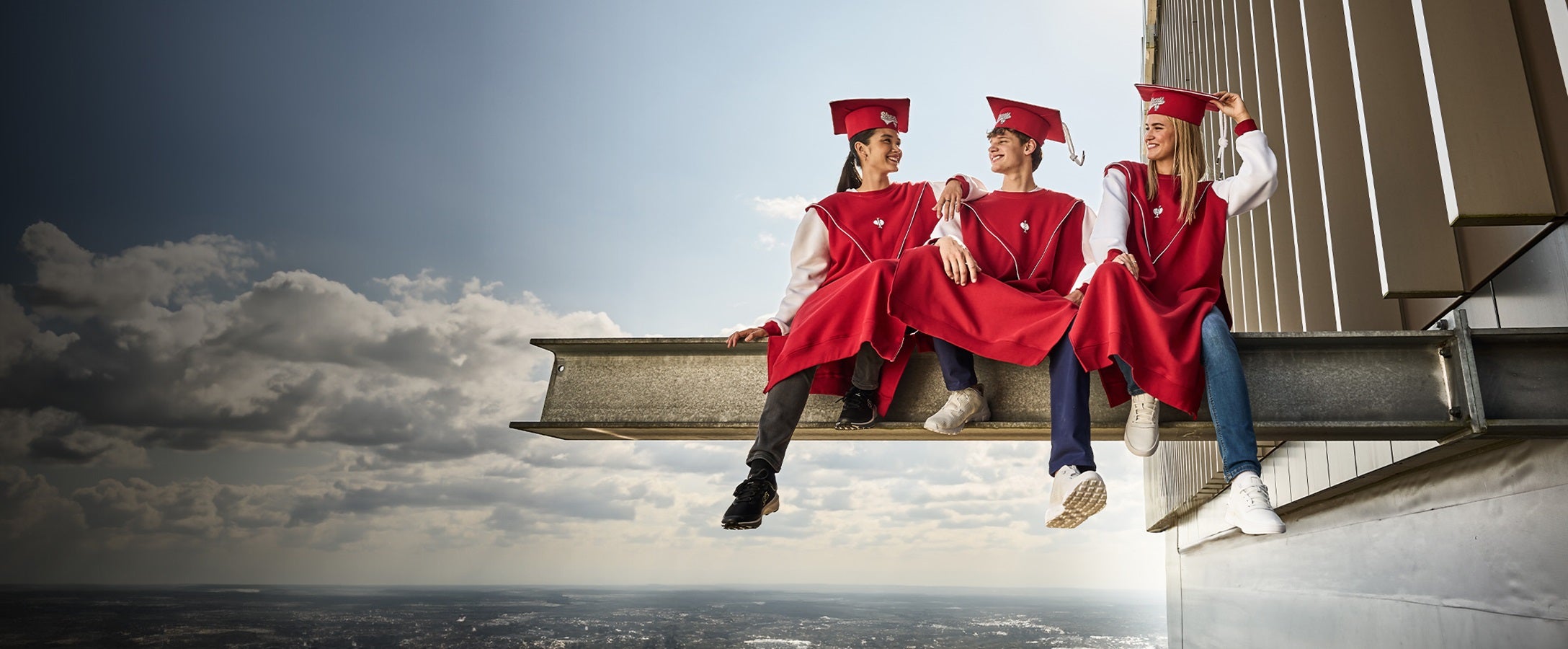 Three students from the Strauss Academy are sitting next to each other and laugh.