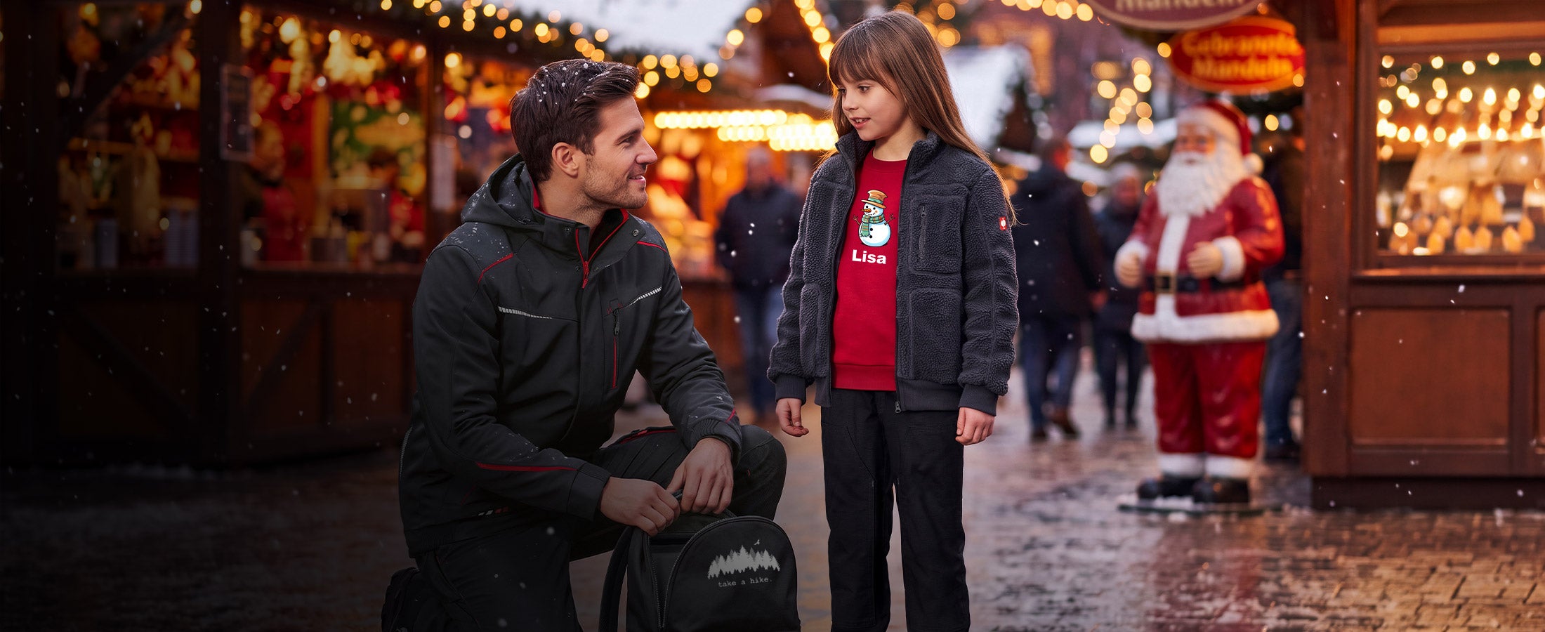 A child and a man at the Christmas market wearing clothes by Strauss.
