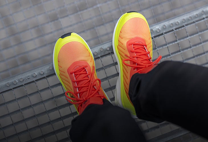 Two shoes in hi-vis yellow and solar red on a metal grid.