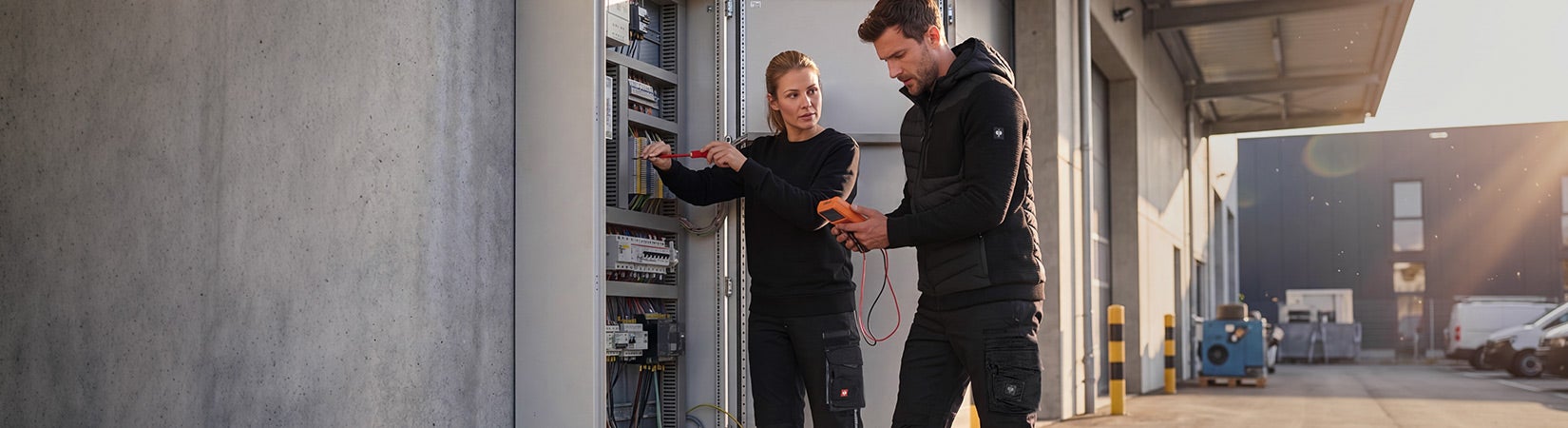 KI-generiert / modifiziert - Two people work on an open electrical cabinet.