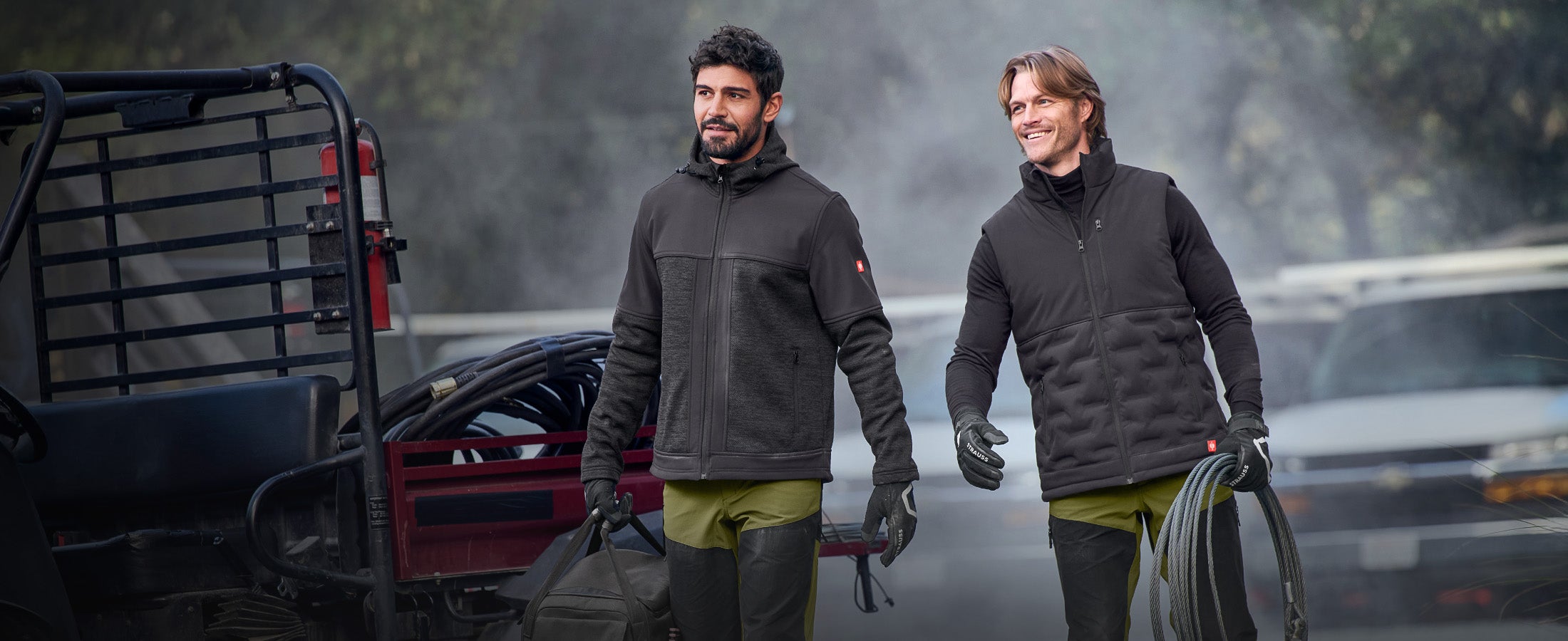 Two men working outside. One in the e.s. Hybrid jacket and one in the e.s. Padded bodywarmer.
