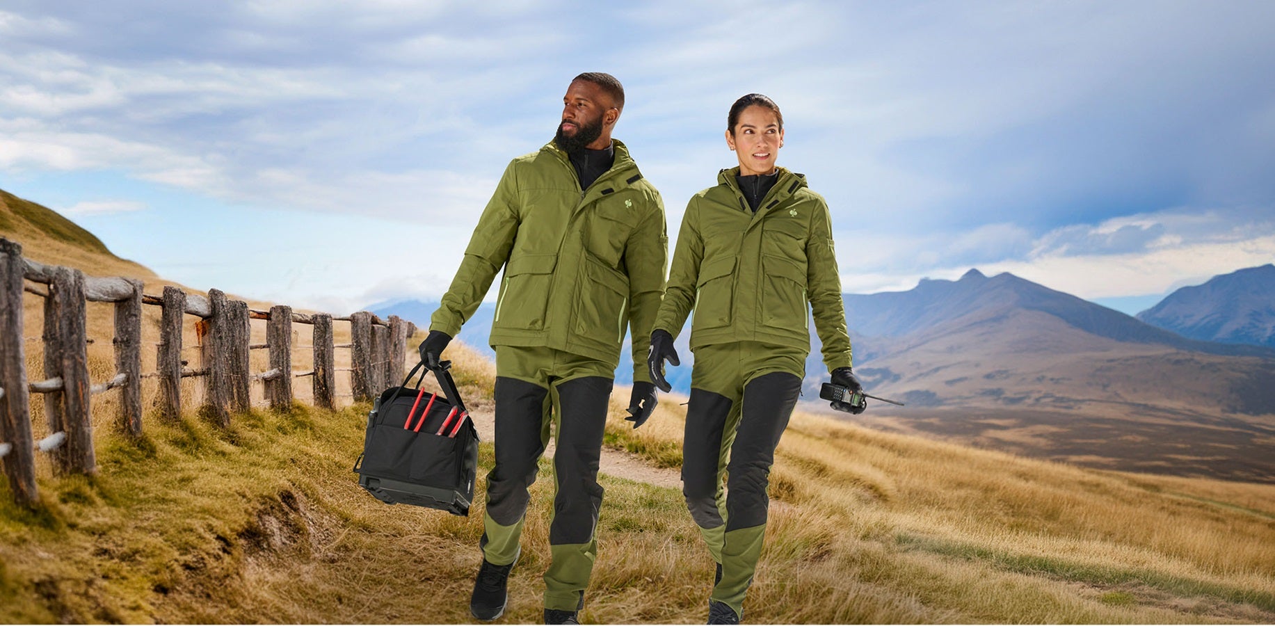 A man and woman wearing the winter jacket e.s.trail and hybrid functional trousers e.s.trail in juniper green/lime green