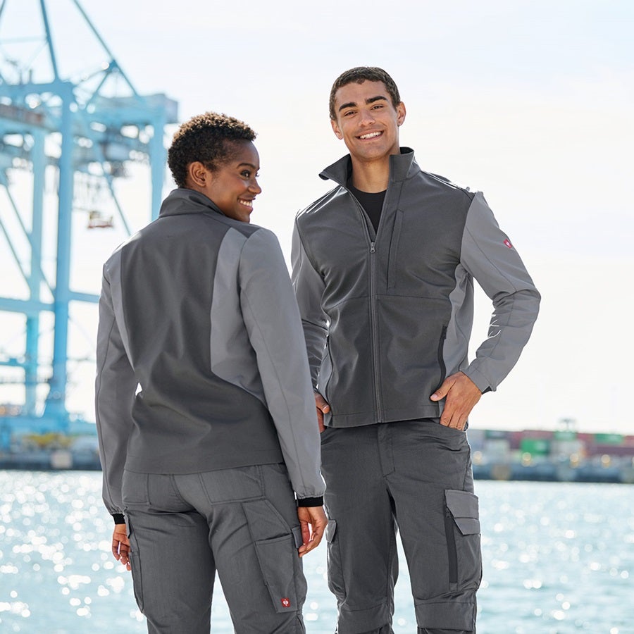 A man and woman wearing the softshell jacket e.s.trail pure in carbon grey/basalt grey
