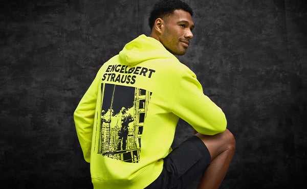 En mand iført en neongul vintage-hoodie. På ryggen er der et cool print med teksten engelbert strauss.