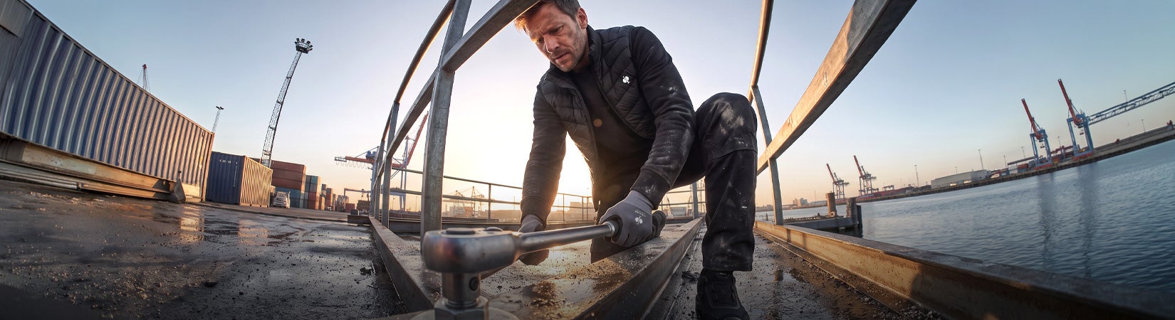 AI-generated / modified – Man in workwear tightens a steel structure with a ratchet beside a harbour basin.