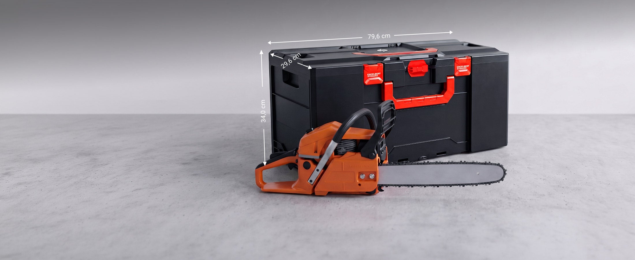STRAUSSbox 340 maxi derrière une tronçonneuse orange.