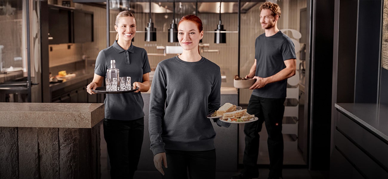 Drei Personen in Arbeitskleidung im Gastronomiebereich