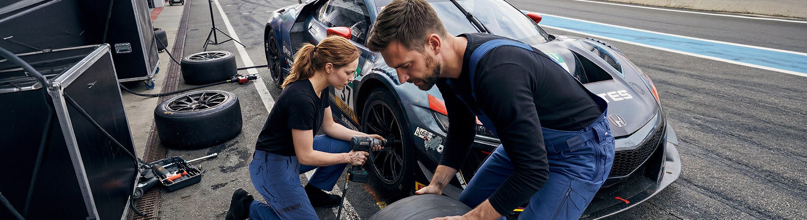 AI-generated / modified - Two people are changing a tire on a race car in the pit lane using tools.