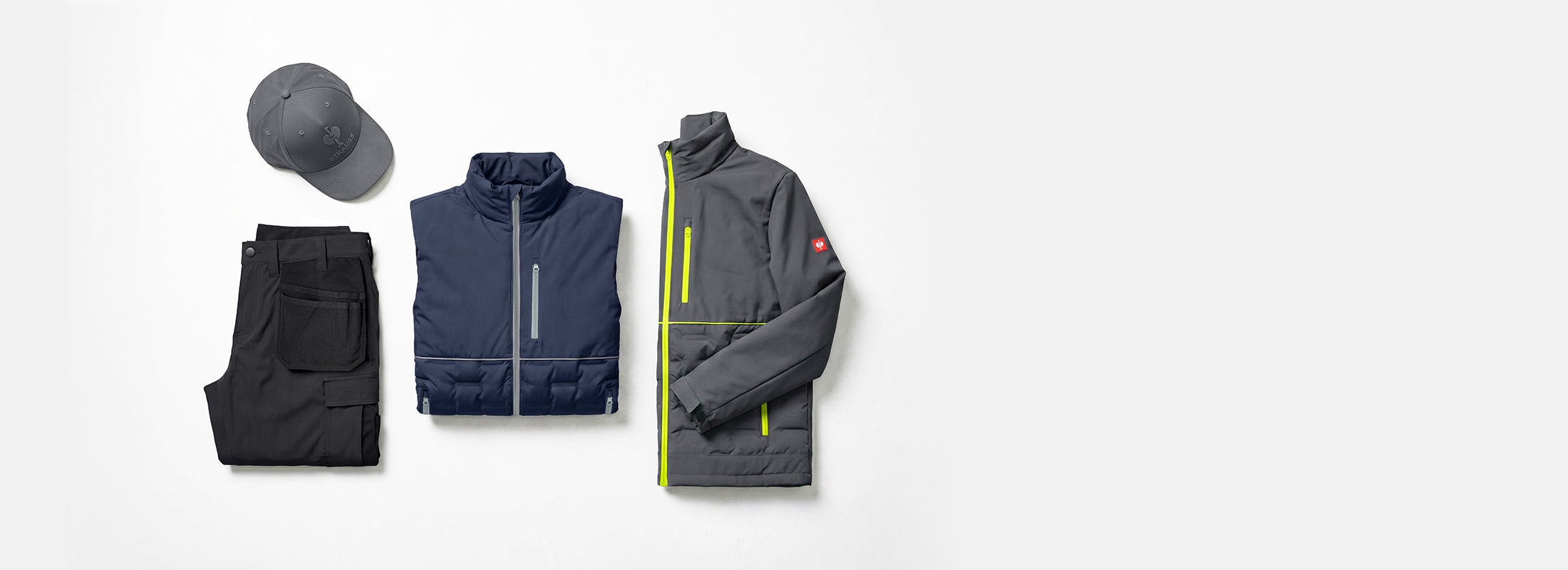 AI-generated / modified - Dark cap, folded trousers, dark blue vest and grey jacket with yellow zips on a light grey background.