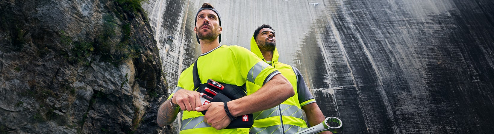 Two men wearing e.s.ambition collection in anthracite/high-vis yellow