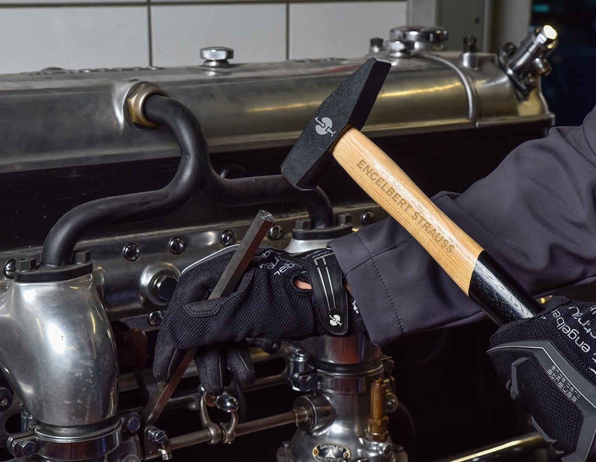 e.s. Schlosserhammer classic mit schwarzem Hammerkopf vor einer Metallmaschine