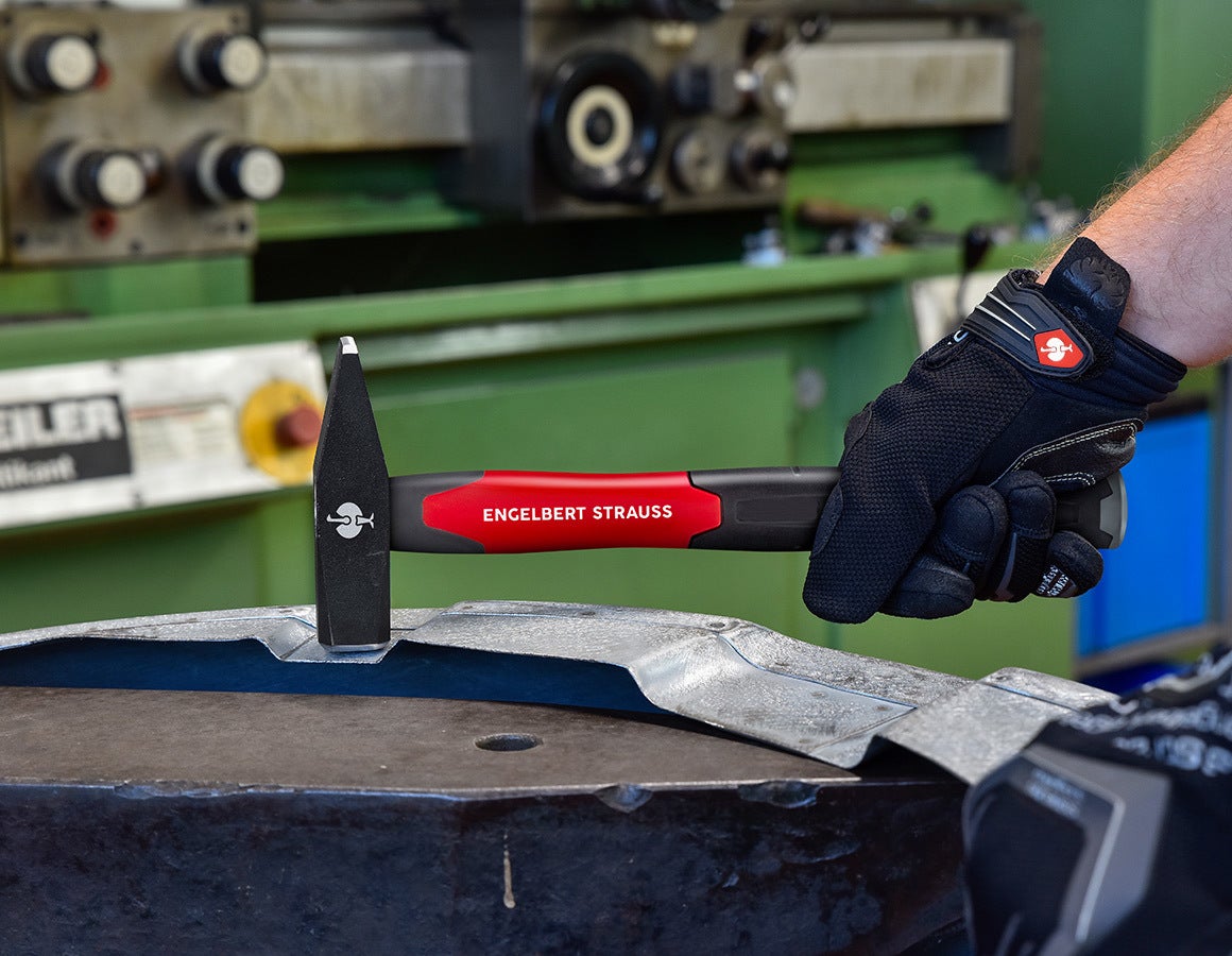 e.s. Schlosserhammer ultimate mit rotem und schwarzem Griff, schwarzem Hammerkopf und weißer Beschriftung beim Bearbeiten eines Metallteils