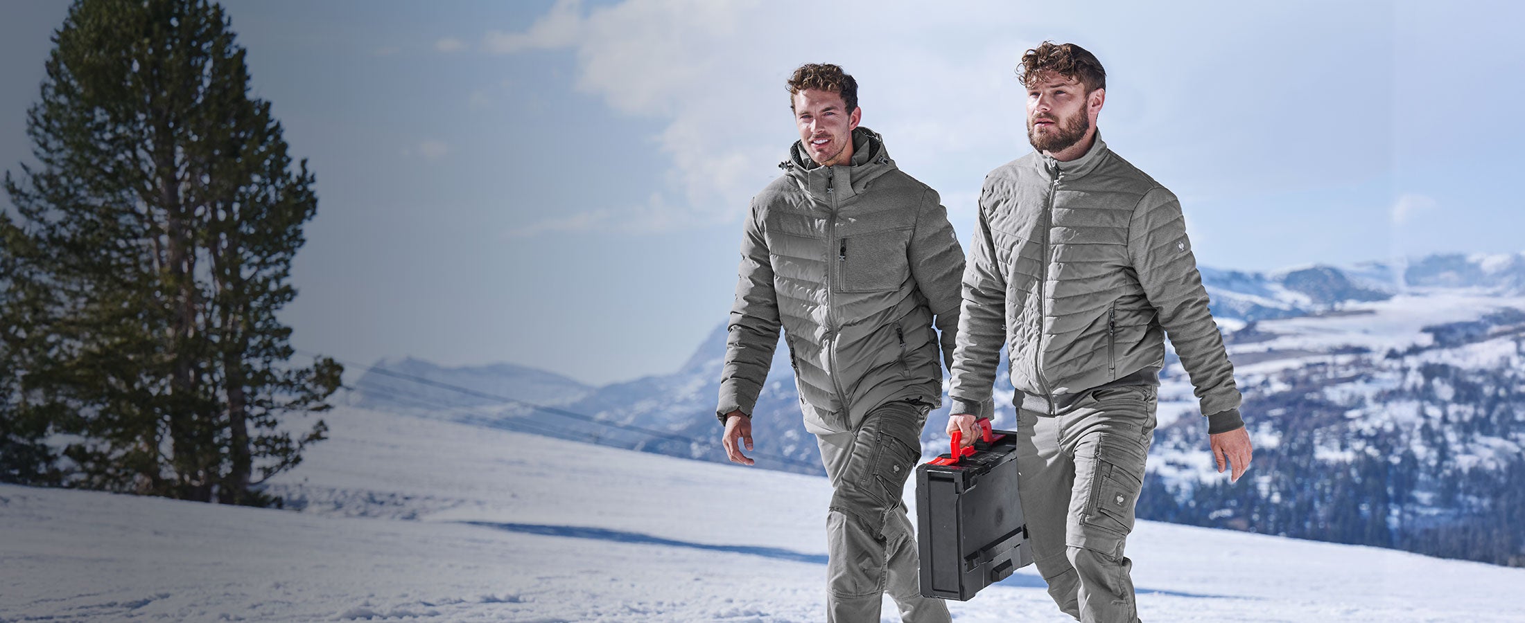 Twee mannen lopen in e.s.motion-jacks door de sneeuw.