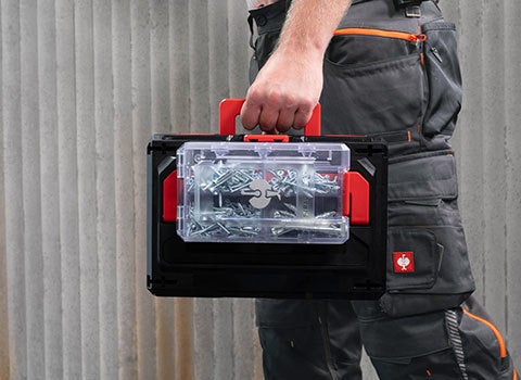 Person carrying a transparent STRAUSSbox x-small, clicked onto a black STRAUSSbox 125 small.