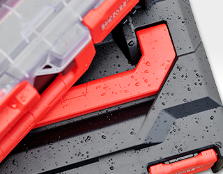 Close-up of a black STRAUSSbox with red latches and water droplets on the surface, indicating splash protection