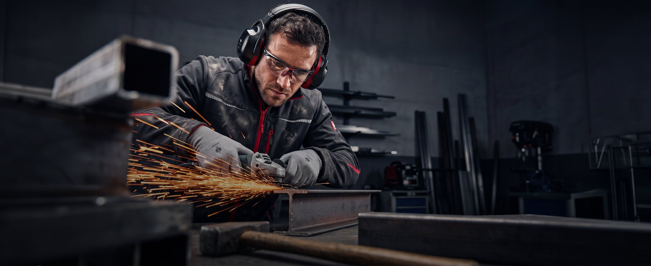 AI-genererad / modifierad: En man med skyddsglasögon, hörselskydd och handskar bearbetar en metallprofil med en vinkelslip.