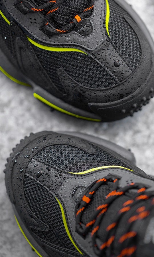 Close-up of S7S safety shoes e.s. Peoria low in black/high-vis orange/high-vis yellow on a concrete background