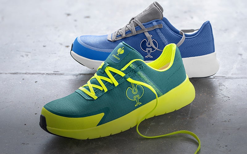 Casual image of SB safety shoes e.s. Taupo low in gentian blue/silver and emerald green/high-vis yellow on a concrete background