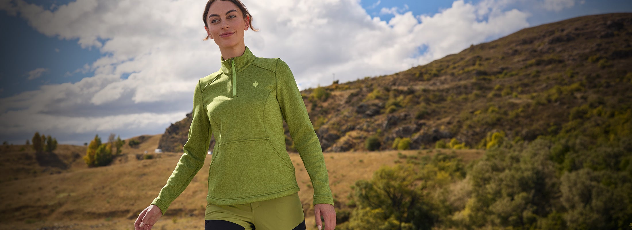Woman in e.s.Trail outdoor clothing in front of a mountain landscape.