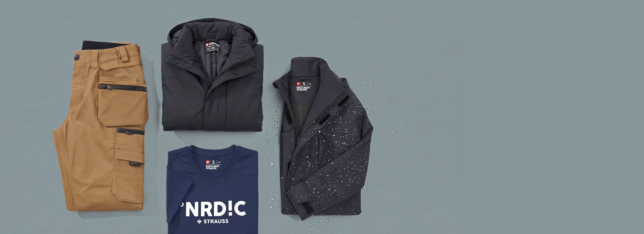 KI-generiert / modifiziert - Hölster-byxa e.s.line.nordic canvas, Vinterparkas e.s.line.nordic, Regnparkas e.s.line.nordic och T-Shirt heavy e.s.line.nordic ligger vikta på en gråblå bakgrund.