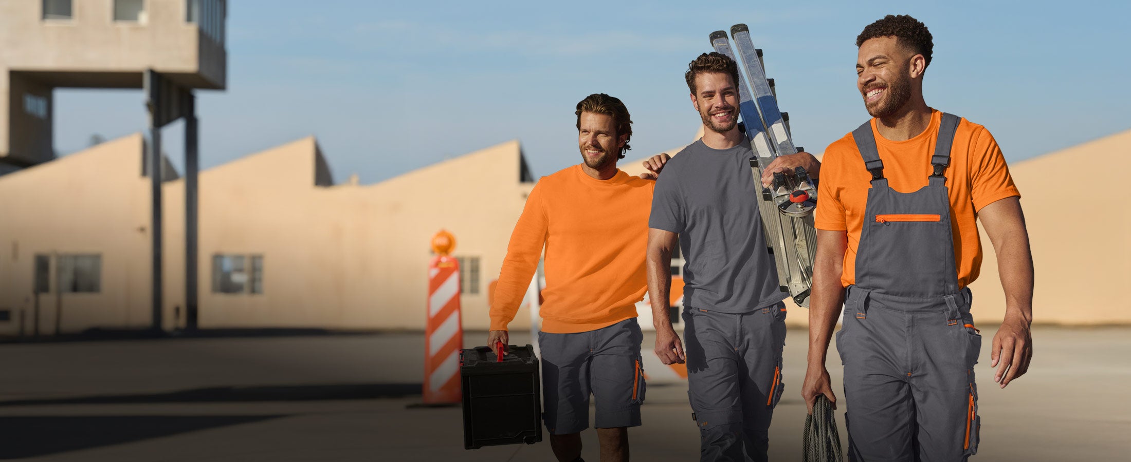 Three men wearing anthracite and warning orange workwear from the e.s.motion 2020 collection